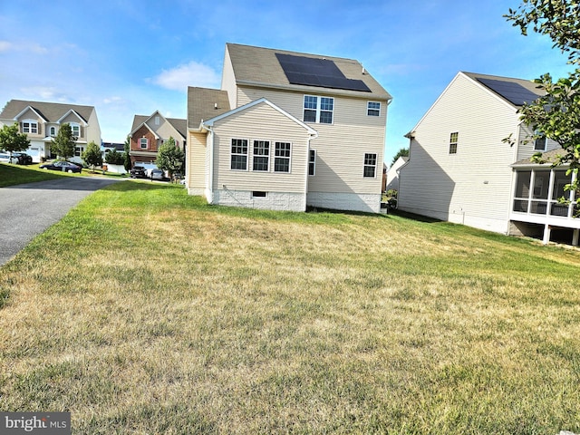 back of property with a lawn and solar panels