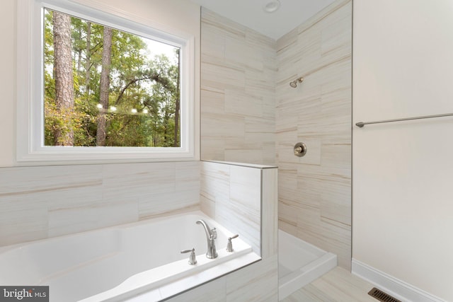 bathroom with shower with separate bathtub and plenty of natural light