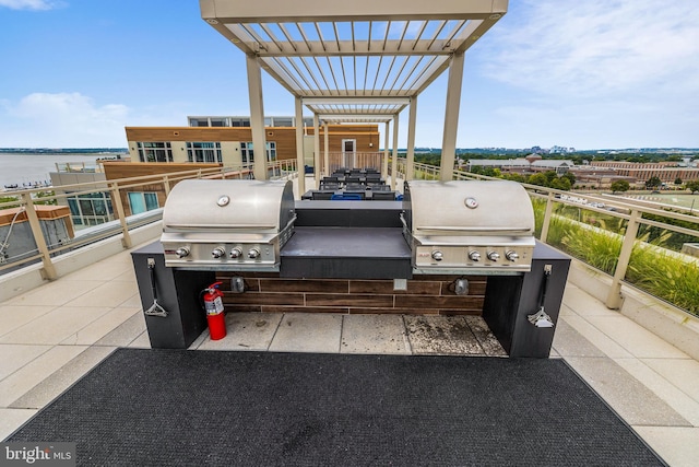 view of patio / terrace featuring a balcony, exterior kitchen, a water view, and a grill