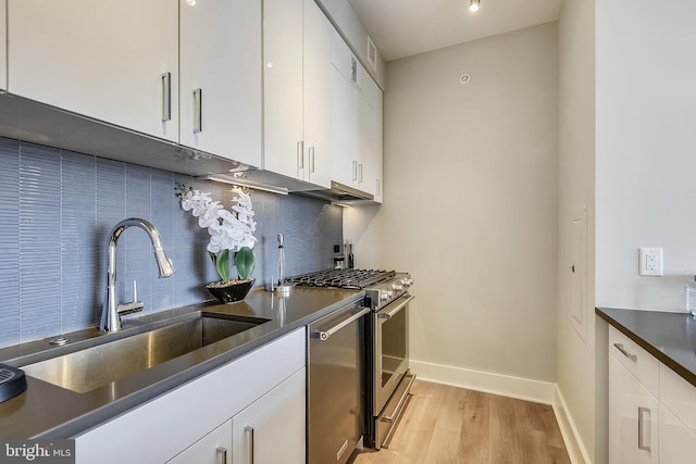 kitchen featuring white cabinetry, light hardwood / wood-style flooring, stainless steel appliances, sink, and decorative backsplash