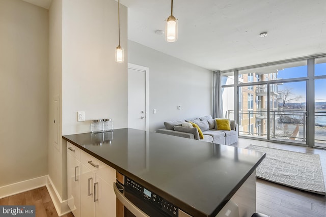 kitchen with hardwood / wood-style floors, a wall of windows, white cabinetry, kitchen peninsula, and hanging light fixtures