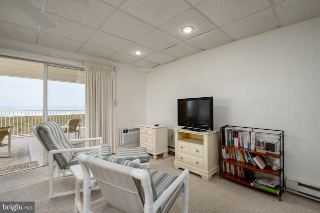 living area featuring a drop ceiling, a wall mounted air conditioner, a baseboard heating unit, and a baseboard radiator