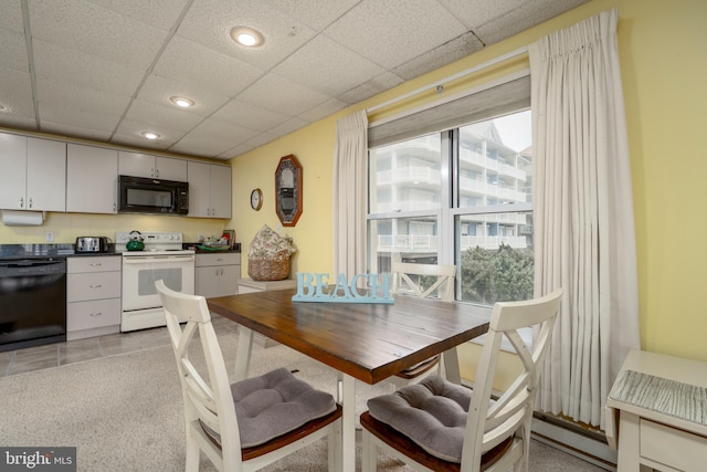 dining area with a baseboard heating unit, plenty of natural light, a paneled ceiling, and light colored carpet