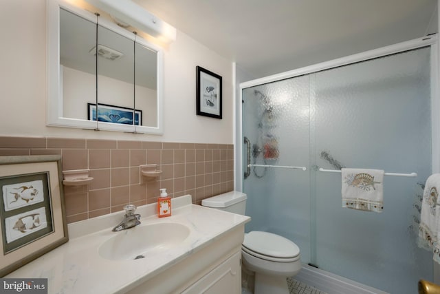 bathroom featuring vanity, tile walls, toilet, and a stall shower