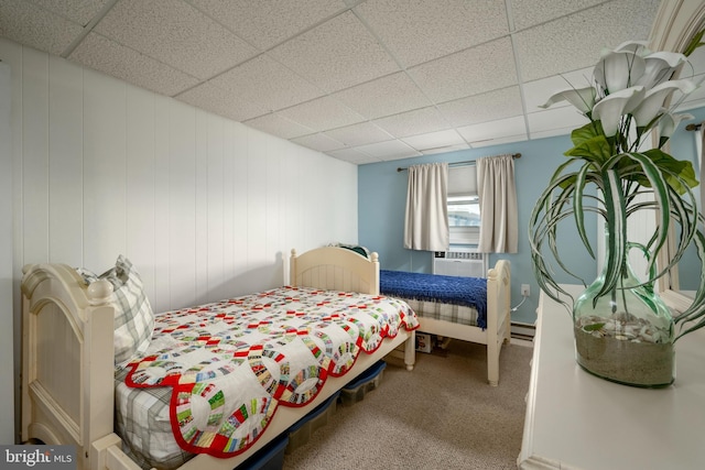 carpeted bedroom with cooling unit, a baseboard heating unit, and a paneled ceiling