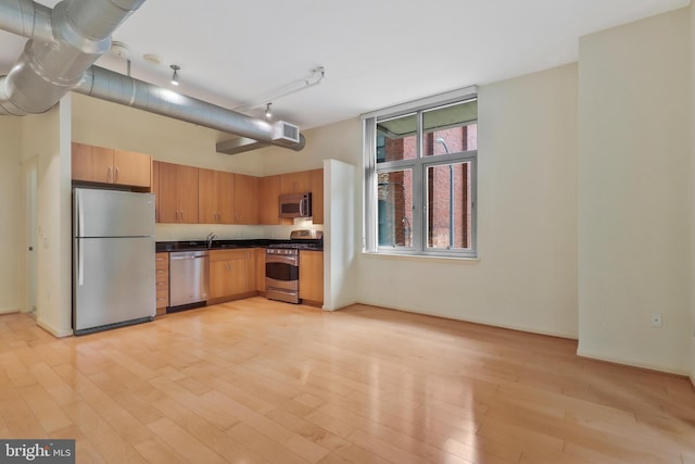 kitchen featuring appliances with stainless steel finishes, rail lighting, sink, and light hardwood / wood-style floors