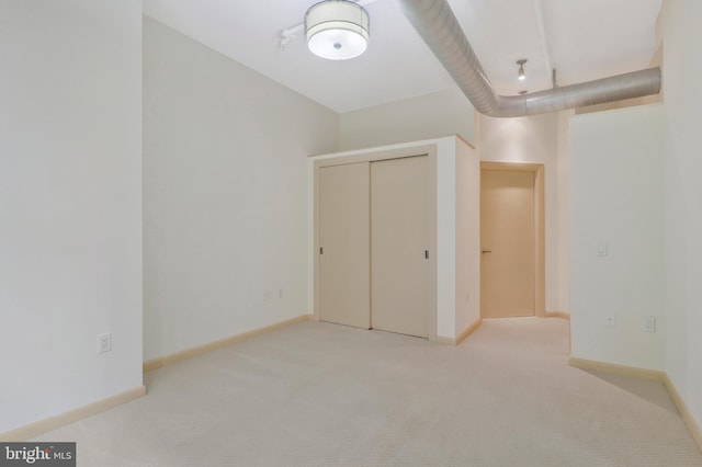 unfurnished bedroom featuring light colored carpet and a closet