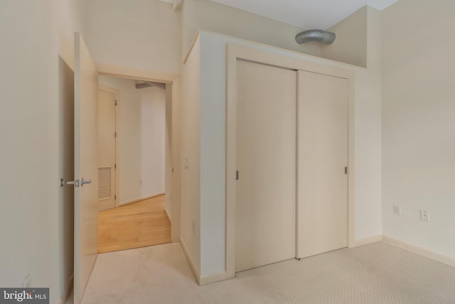 unfurnished bedroom featuring light colored carpet and a closet