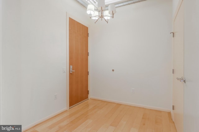 empty room featuring light wood-type flooring and a notable chandelier