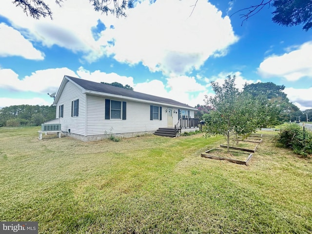 back of property with a vegetable garden, a yard, and a wooden deck