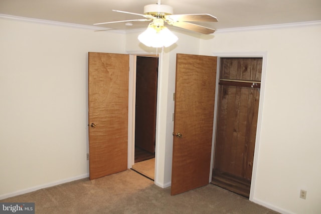 unfurnished bedroom with ornamental molding, a closet, carpet floors, baseboards, and ceiling fan