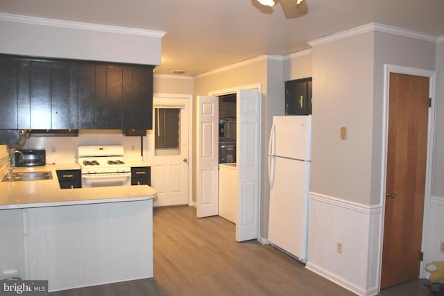 kitchen with white appliances, wood finished floors, crown molding, and a sink