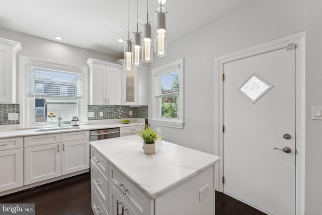 kitchen with a kitchen island, sink, white cabinets, and decorative backsplash