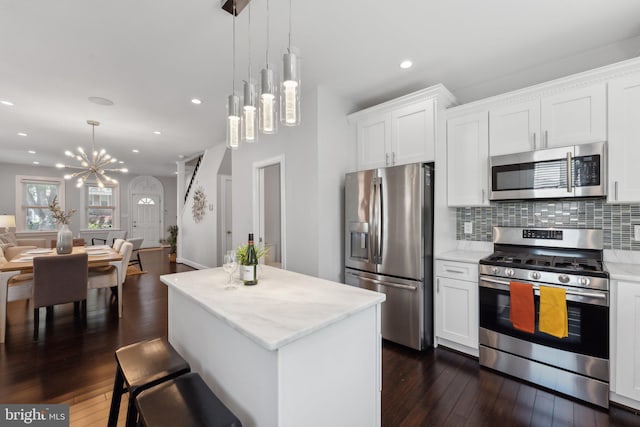 kitchen featuring dark hardwood / wood-style flooring, stainless steel appliances, a center island, and white cabinets