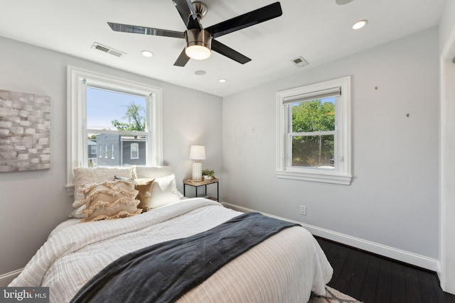 bedroom with dark wood-type flooring, multiple windows, and ceiling fan