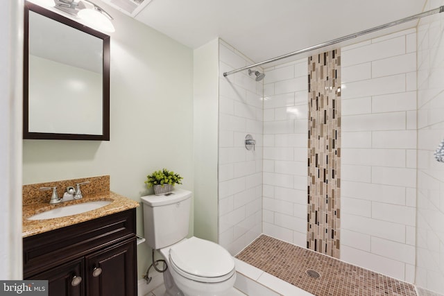 bathroom with vanity, toilet, and a tile shower