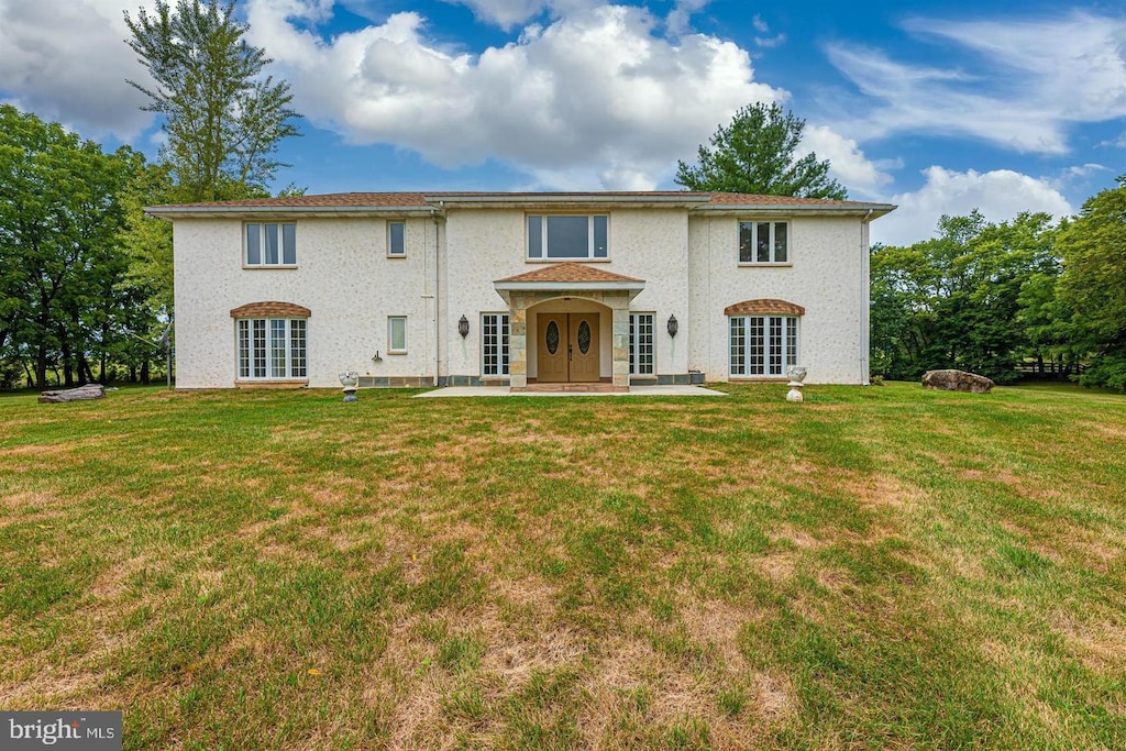 view of front facade featuring a front lawn, a patio area, and french doors