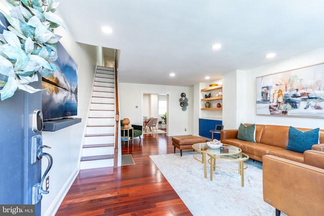 living room with built in shelves and dark hardwood / wood-style floors