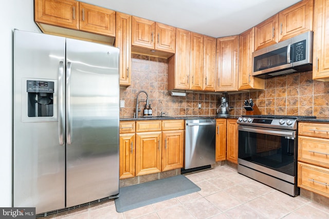 kitchen with appliances with stainless steel finishes, dark stone counters, decorative backsplash, and light tile patterned floors