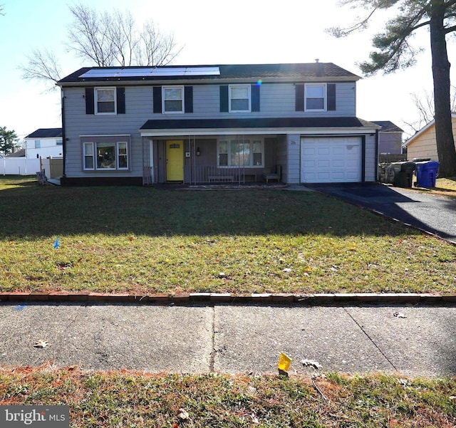 traditional-style house featuring aphalt driveway, a garage, covered porch, and a front yard