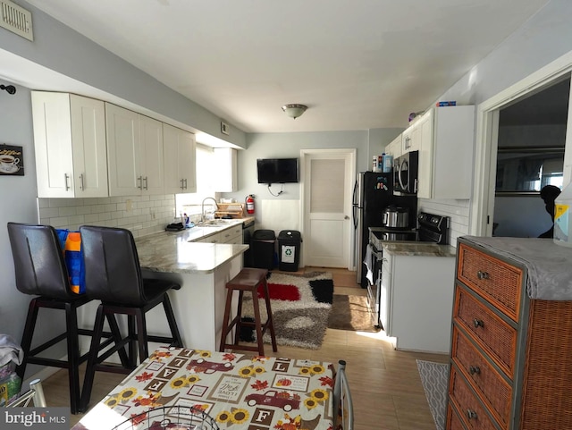 kitchen with stainless steel microwave, visible vents, electric range oven, white cabinets, and a sink