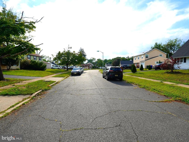 view of road featuring sidewalks, a residential view, and street lighting