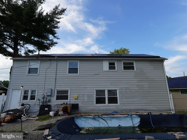 rear view of house featuring a covered pool