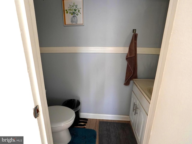 bathroom with toilet, vanity, baseboards, and wood finished floors