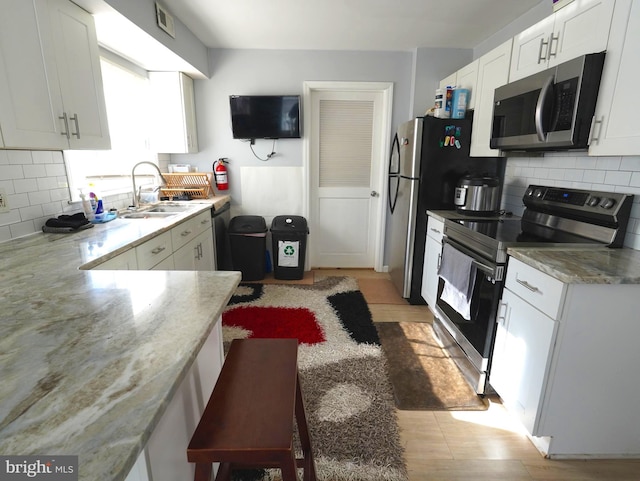 kitchen featuring visible vents, decorative backsplash, white cabinets, stainless steel appliances, and a sink