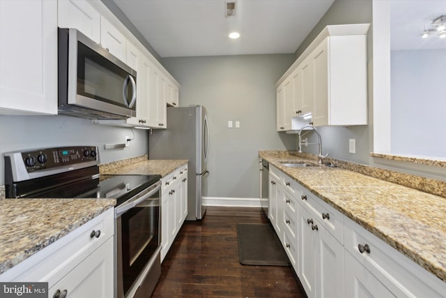 kitchen featuring light stone countertops, appliances with stainless steel finishes, white cabinetry, sink, and dark hardwood / wood-style floors