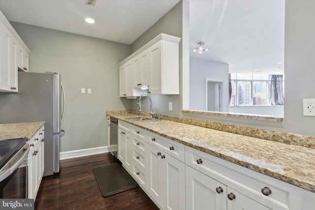 kitchen featuring white cabinets, appliances with stainless steel finishes, light stone countertops, dark hardwood / wood-style flooring, and sink