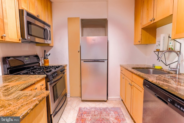 kitchen featuring stainless steel appliances, light stone counters, sink, and light tile patterned flooring