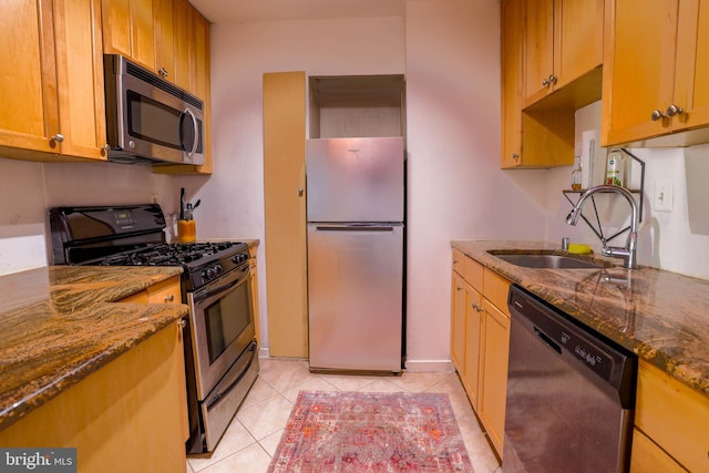 kitchen featuring stone countertops, light tile patterned floors, stainless steel appliances, and sink