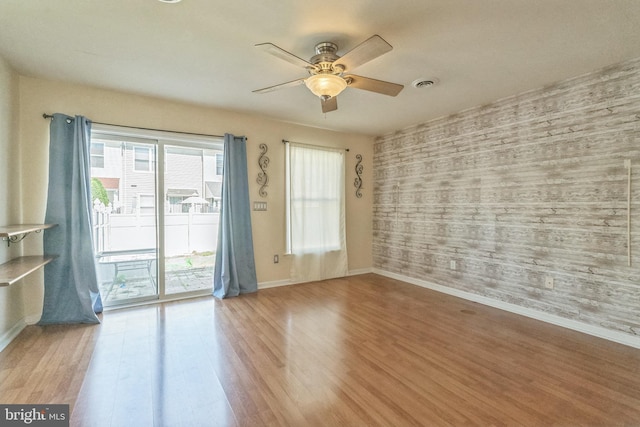 empty room featuring ceiling fan, wood finished floors, visible vents, and baseboards