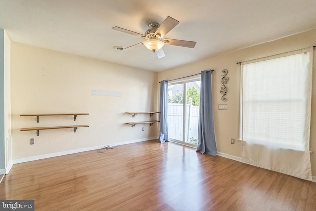 spare room with baseboards, wood finished floors, and a ceiling fan