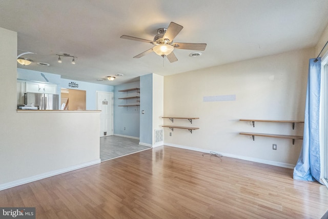 unfurnished living room featuring a ceiling fan, wood finished floors, visible vents, and baseboards