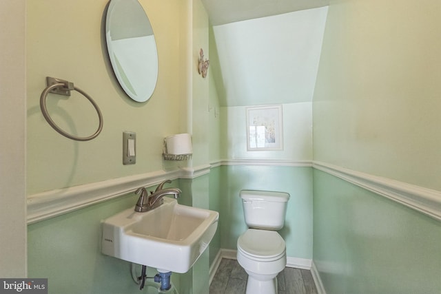 bathroom with toilet, wood finished floors, baseboards, and a sink