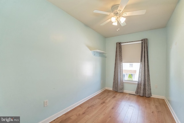 spare room featuring light wood finished floors, visible vents, ceiling fan, and baseboards