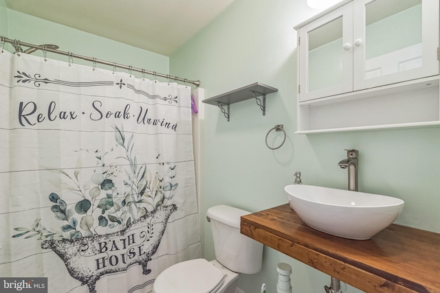 full bathroom featuring curtained shower, toilet, and a sink