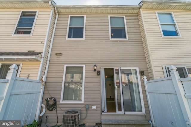 rear view of house featuring central AC unit and fence