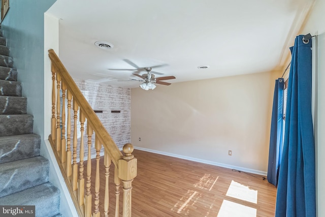 stairway featuring ceiling fan and hardwood / wood-style floors