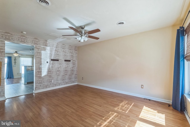 empty room with visible vents, baseboards, and wood finished floors