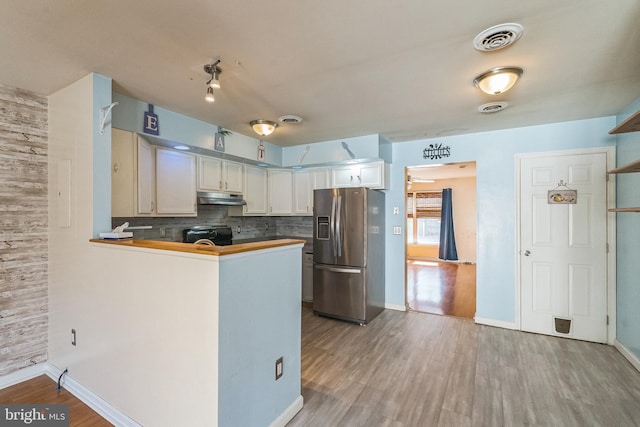 kitchen featuring visible vents, decorative backsplash, black range with electric stovetop, under cabinet range hood, and stainless steel fridge