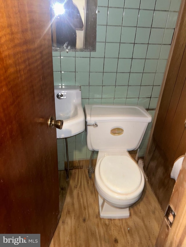 bathroom featuring toilet, wood-type flooring, sink, and tile walls