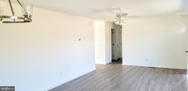 empty room featuring baseboards, ceiling fan, and light wood finished floors