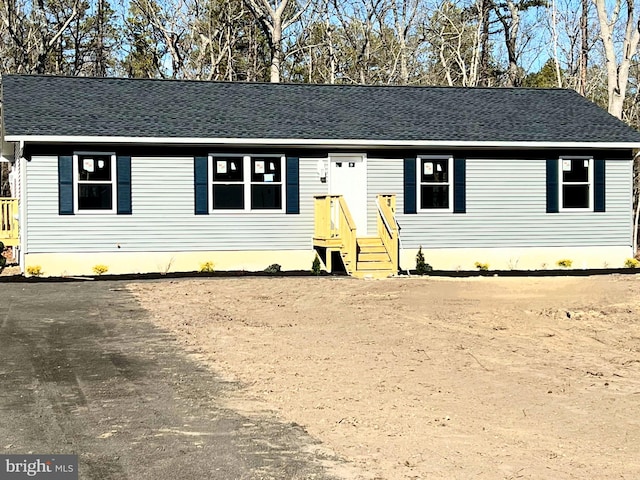 view of front of house featuring driveway and roof with shingles