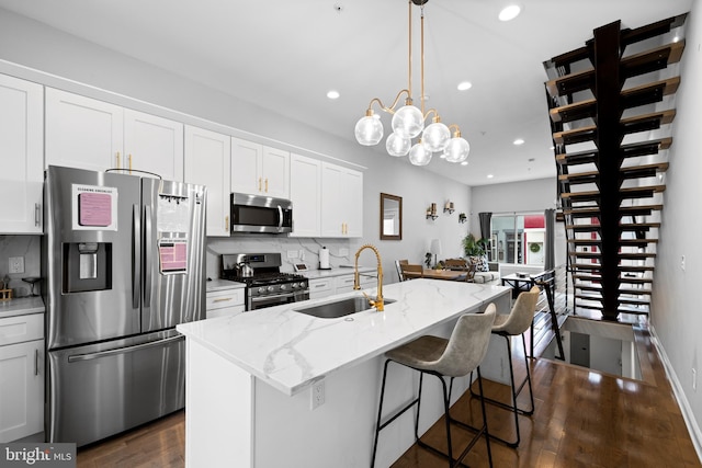 kitchen featuring a kitchen island with sink, pendant lighting, sink, dark wood-type flooring, and appliances with stainless steel finishes