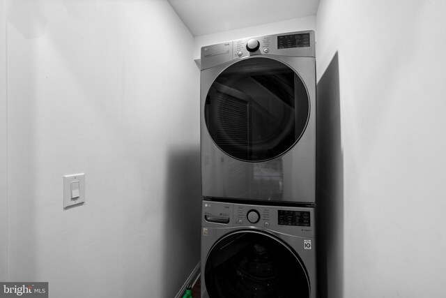 clothes washing area featuring stacked washer and clothes dryer