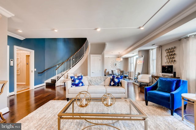 living area featuring stairs, wood finished floors, baseboards, and ornamental molding