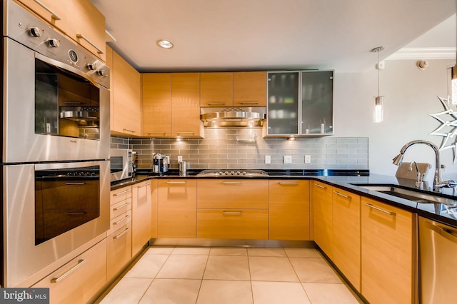 kitchen with tasteful backsplash, under cabinet range hood, pendant lighting, stainless steel appliances, and a sink